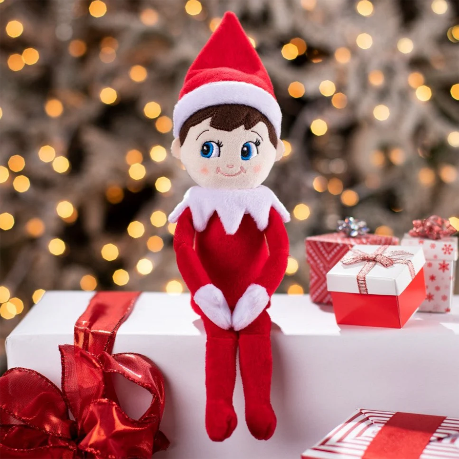 Elfo en la estantería con traje rojo y blanco, sentado junto a regalos